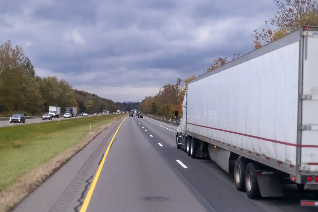 White semi truck driving on a multi-lane interstate highway with traffic ahead, illustrating truck route planning